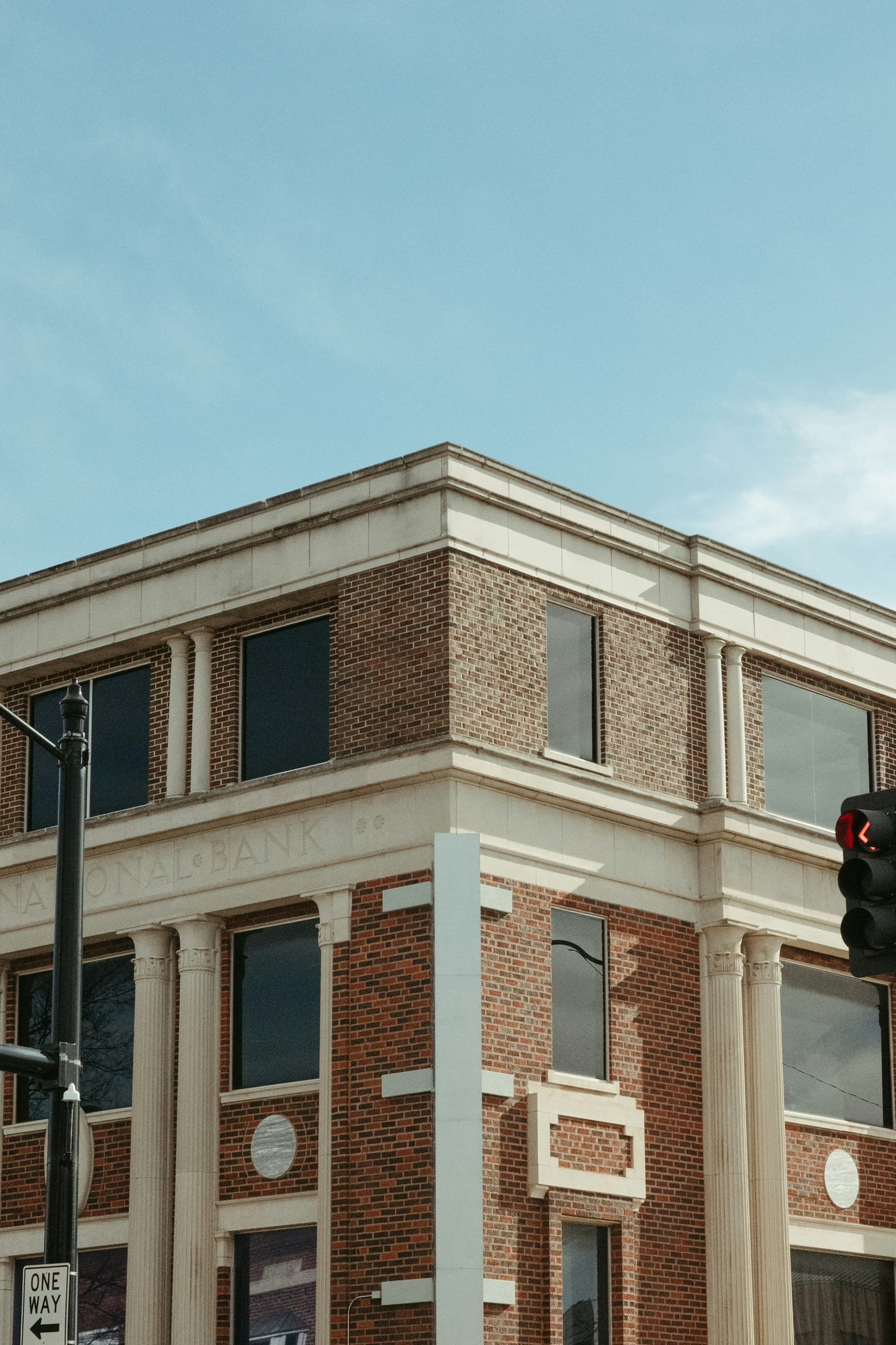 A historic brick-and-limestone former bank building with columns on a downtown corner.