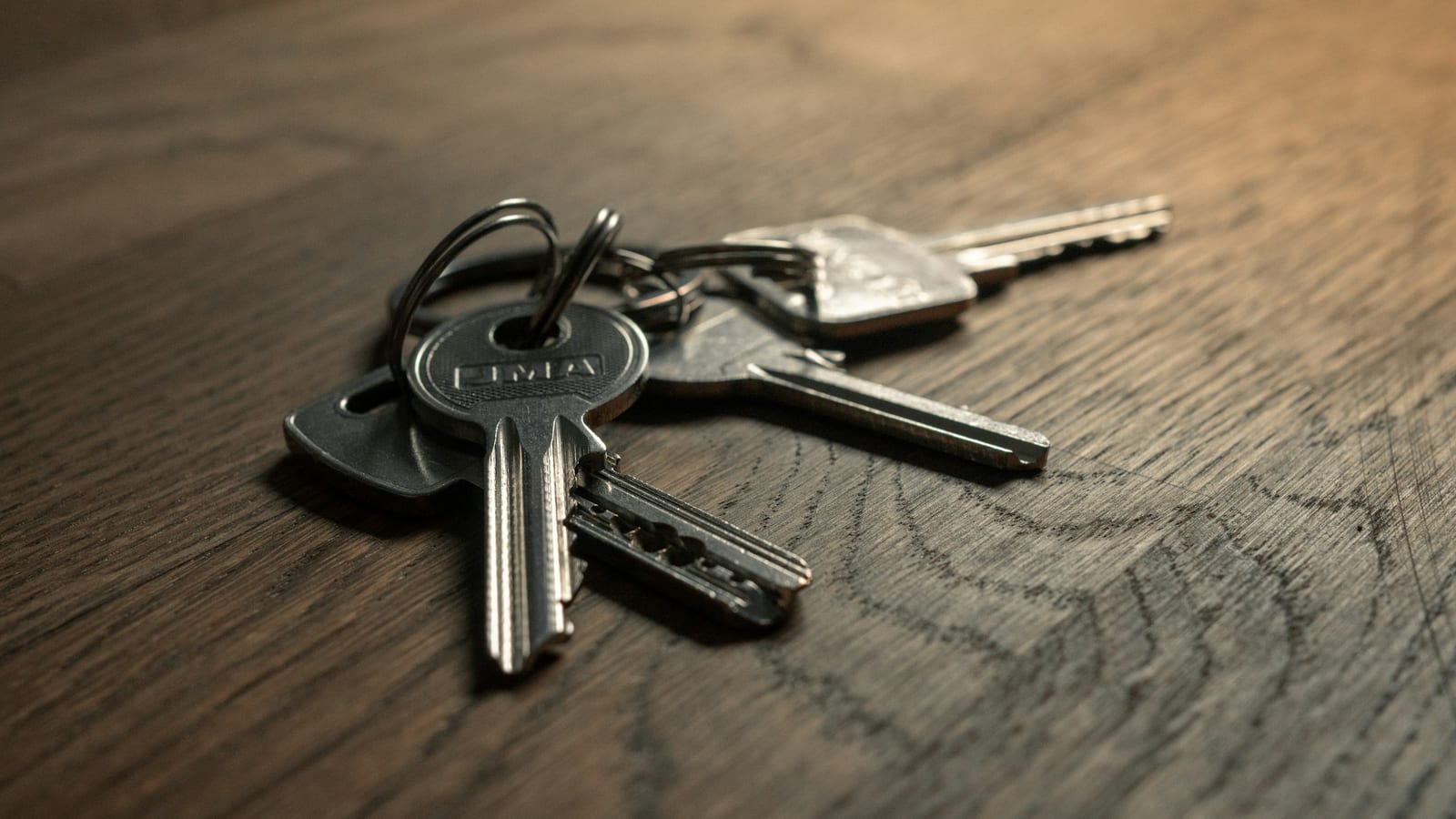 A set of house keys resting on a dark wooden table.
